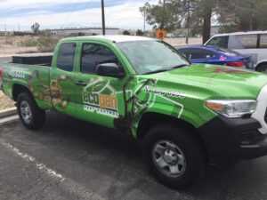 A green Ecogenpest pickup truck is parked in a lot. The vehicle features images of insects and company branding, displaying the Ecogen logo, phone number, and license number on its side.